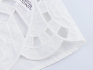Gros plan sur les détails de broderie blanche et motifs floraux sur tissu en coton pur