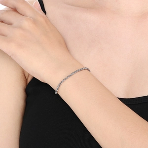 Macro close-up of a silver cross chain bracelet with pearls on a female wrist