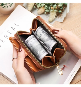Brown leather short wallet with smooth zipper showing spacious bill compartment capacity
