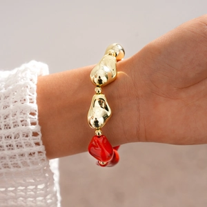 Détail du bracelet bohème avec des perles acryliques irrégulières dorées et rouges