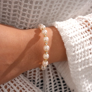 Détail d'un bracelet élégant en perles avec accents en strass dorés sur le poignet