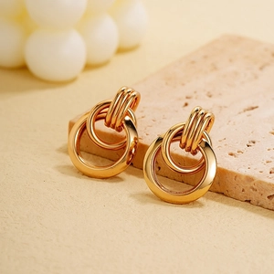 Detailed macro shot of gold-plated nested loop earrings on a natural stone base