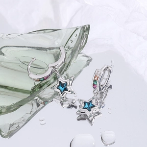 Macro shot of silver star drop earrings with blue crystal and multi-color rhinestones