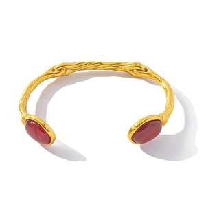 Detail of twisted 18K gold-plated titanium bracelet with red-brown gemstone accents