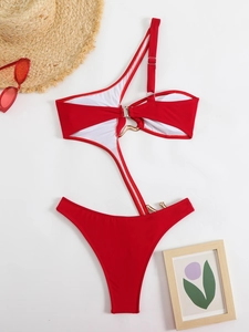Flat lay of red cutout one-piece swimsuit with gold hardware and vacation props