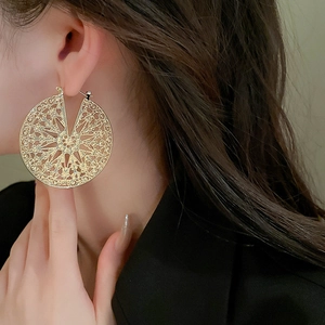 Gros plan de boucles d'oreilles disque doré évidé avec motifs filigranes vintage