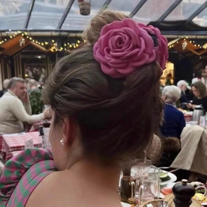 Dettaglio di una grande molletta per capelli a forma di rosa rosa indossata su uno chignon