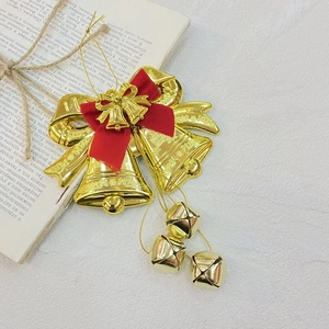 Decorative golden Christmas double bell ornament with red bow on white textured background