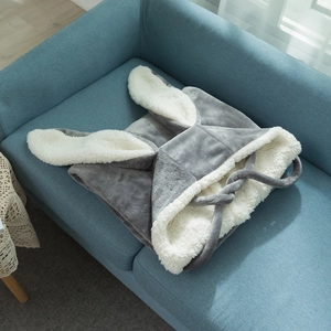 Detail of hooded rabbit ear blanket with lamb wool lining folded on a blue sofa