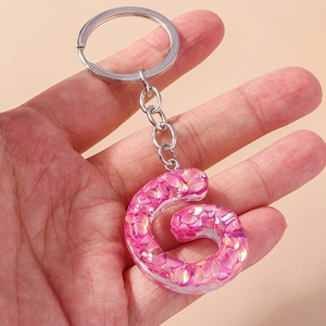 Detailed macro of pink glitter resin letter keychain with silver metal ring and chain