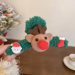 Detail showing the green plush Christmas hair claw clip with reindeer and Santa charms