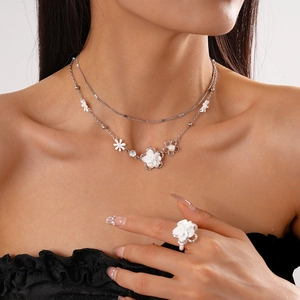 Primo piano di un set collana e anello floreale con petali bianchi e catene d'argento