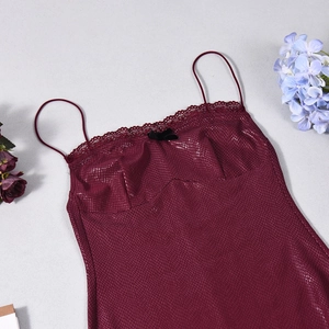 Close-up of wine red faux snakeskin top with lace trim and velvet bow detail