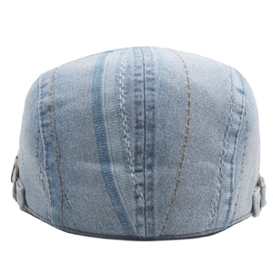 Detail of washed denim beret with vintage vertical stitching and bronze metal buckle