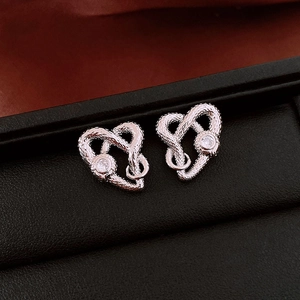 Macro shot of silver heart snake knot stud earrings with round brilliant cubic zirconia
