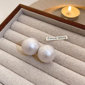Macro detail of silk-texture white pearl earrings in a premium wooden jewelry box