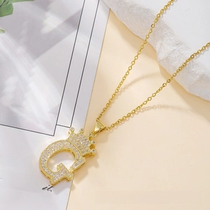 Close-up of golden crown initial G necklace with white cubic zirconia and cross chain