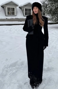 Detailed close-up of a slim fit long black wool coat with shawl collar and waist design