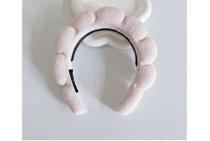 Detailed top view of pink puffy sponge headband with inner non-slip teeth on white display