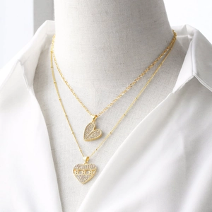 Gold double-layered necklace with zircon heart pendants and star detail on white shirt