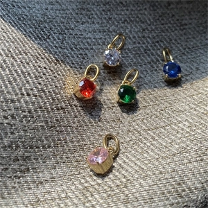Gros plan de cinq pendentifs en cristal sertis à quatre griffes sur tissu texturé