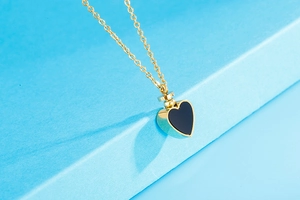 Détail du pendentif coeur doré avec incrustation noire et bouchon à vis fonctionnel de luxe