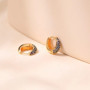 Macro detail of 18K gold-plated earrings with pave-set deep blue zircon crystals