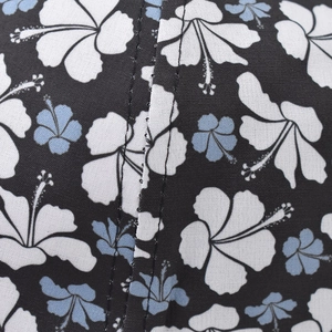 Detail shot of black floral cotton fabric with blue hibiscus print and reinforced double stitching