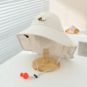 Detail of baby sun hat with cute bear patch, wide brim, and red whistle on drawstring