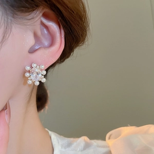 Close-up of elegant flower stud earring with central zircon and pearl petals on model