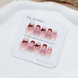 Pink cat eye press-on nails with 3D brown bows and red dots on white display card