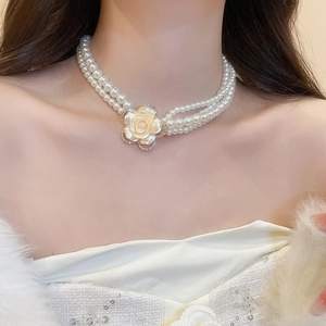 Close-up of double-layer pearl necklace with a diamond-encrusted cream rose pendant