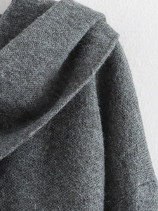 Dettaglio della trama in maglia grigio scuro e cuciture sulle spalle del cappotto
