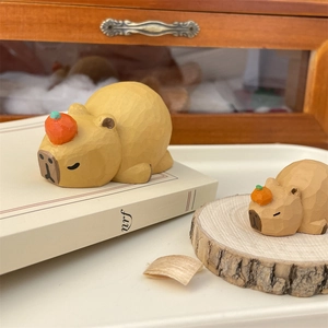 Detail of hand-carved wooden capybara figurines with orange accents and faceted finish