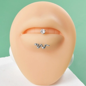 Detail of silver snake labret and zircon stud on a silicone lip model for piercing