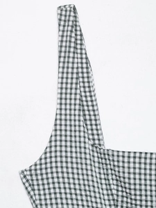 Détail de la couture et de la bretelle sur une robe midi à carreaux noirs et blancs