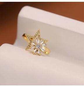 Close-up of golden spinning windmill ring with sparkling zircon star and sunburst design