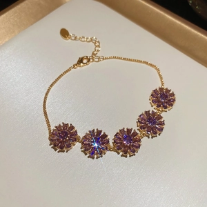 Macro view of 18k gold plated bracelet with purple zircon flower pendants and O-chain detail