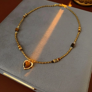 Gros plan d'un collier de perles dorées et pendentif coeur sur fond en velours