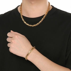 Detailed view of men's golden hip hop emperor chain necklace and bracelet set on a model
