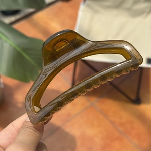 Detailed macro view of an amber resin hair claw clip showing a clear texture in sunlight