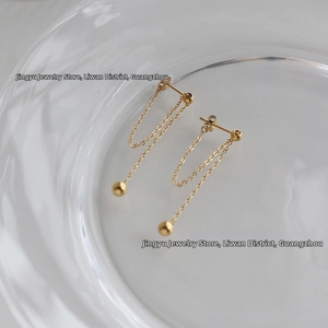 Elegant gold drop earrings featuring a long tassel chain and gold beads on a water ripple tray