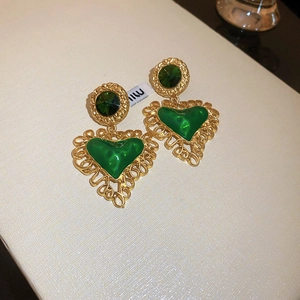 Detail of vintage heart-shaped gold drop earrings with green stones and lace trim