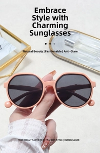 Close-up of peach resin sunglasses featuring dark grey lenses and round hinge detail