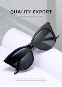 Detail shot of black cat-eye sunglasses with dark grey lenses on a white display stand