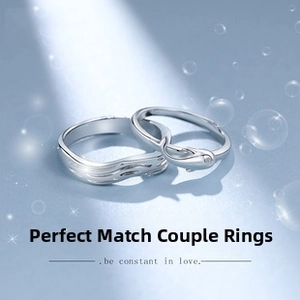 Detail of silver dolphin and wave rings for couples on a dreamy blue background