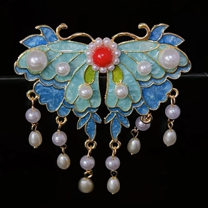 Détail de la pince papillon avec ailes en émail bleu et glands de perles