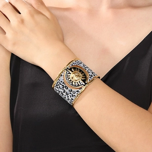 Detail of gold sun mask cuff bracelet with leopard pattern on model in black silk