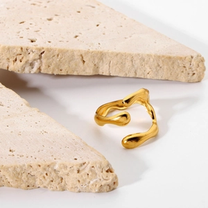 Detailed view of gold irregular fluid texture ring set on natural stone props