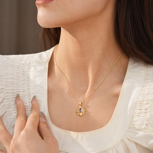 Detail of vintage gold necklace featuring a purple zircon rhombus pendant on model